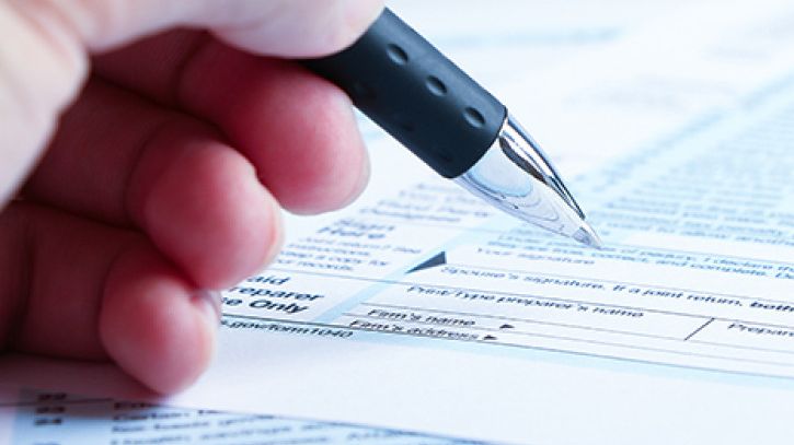 Hand signing a KiwiSaver first home withdrawal application form